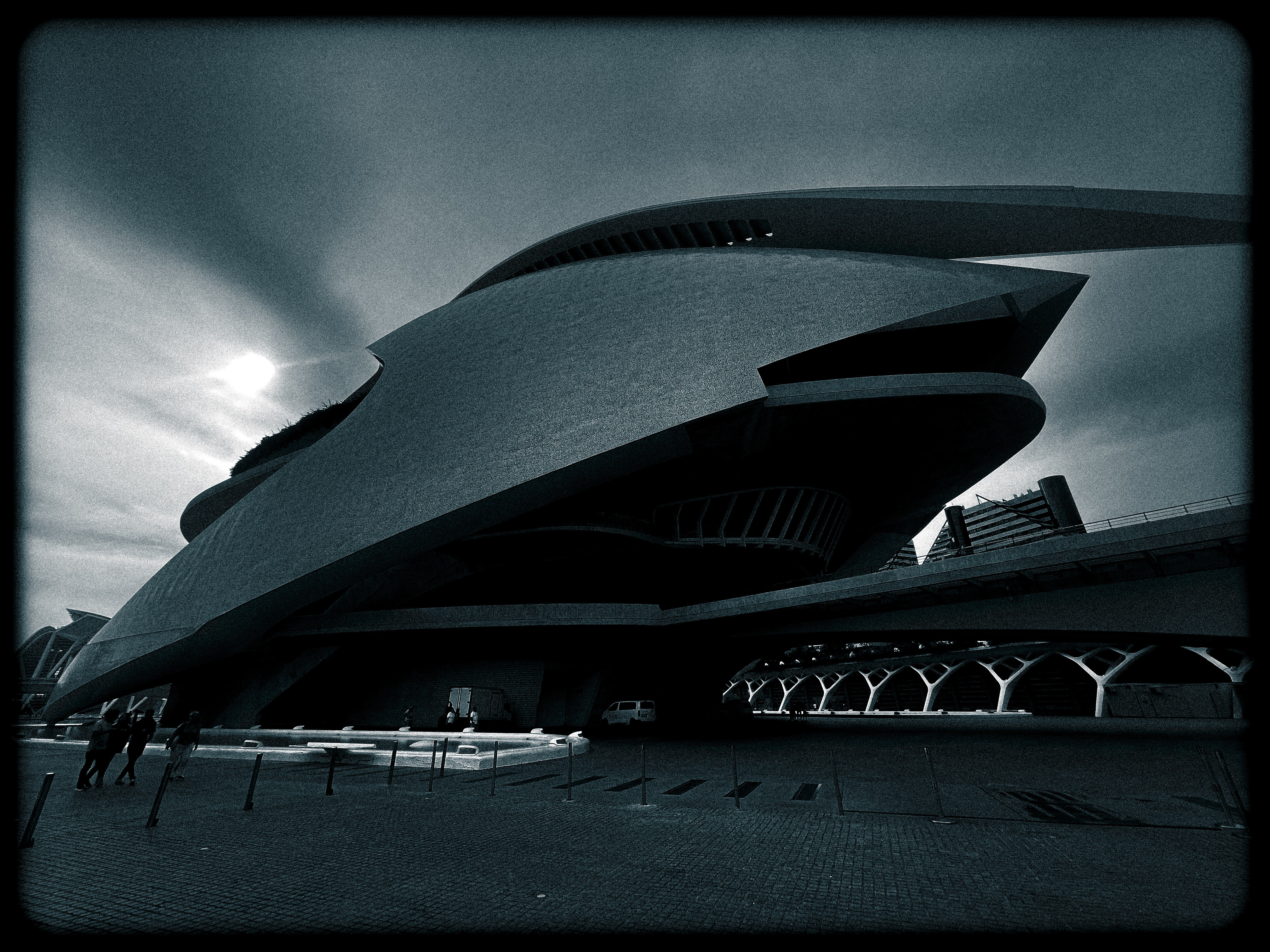 a black and white photo of a building with a cloudy sky